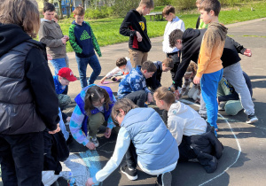 Uczniowie z klasy 5a podczas twórczej pracy na boisku szkolnym związanej z Dniem Ziemi.