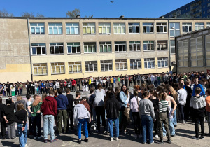 Wszyscy uczestnicy biorący udział w obchodach Dnia Ziemi obserwują lot drona nagrywającego finał akcji z okazji Dnia Ziemi.