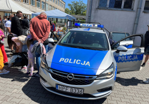 Policyjne stanowisko – radiowóz, policjanci z broszurami i odblaskami