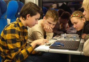 Szymon, Natalia, Franciszek, Michał podczas jazdy pociągiem na ogólnopolski konkurs HackEdu montują robota z elementów Arduino Starter Kit.