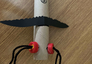 Papierowy owad wykonany z długiej, papierowej rolki, drucików kreatywnych i plastikowych nakrętek