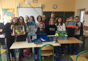 Uczniowie klasy 6b prezentują prace przestrzenne w których elementy plastyczne umieszczone są w papierowych kartonach i słoikach.
