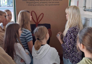 Grupa uczniów podczas zajęć warsztatowych prowadzonych przez animatora w EkoEksperymentarium zbudowanym na planie mieszkania.