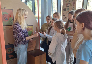 Grupa uczniów podczas zajęć warsztatowych prowadzonych przez animatora w EkoEksperymentarium zbudowanym na planie mieszkania.