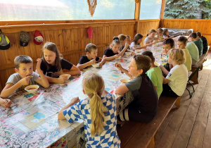 Poczęstunek. Uczestnicy jedzą zupę pomidorową przygotowaną przez Gospodynię