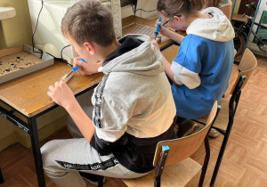 Uczniowie wypalają wypalarką wzory na swoich ostrzałkach