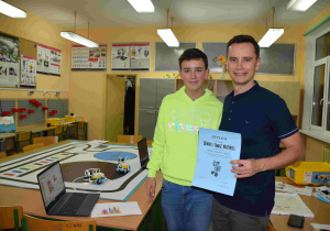 Uczestnicy zajęć – syn i tata stoją w pracowni Laboratorium Przyszłości z dyplomem za udział w zajęciach Rodzic + Dziecko = Robot
