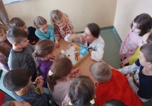Przedszkolaki obserwują przebieg doświadczenia chemicznego.
