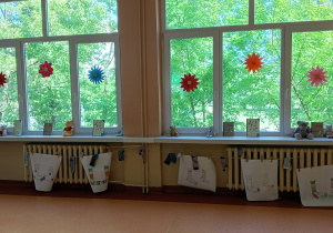 Na parapecie stoją książki o Muminkach, o przygodach skarpetek oraz pluszowe miśki. Na szybach wiszą kolorowe kwiaty. Na dole – skarpety zaprojektowane przez dzieci z Przedszkola Miejskiego nr 55 w Łodzi.