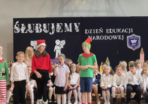 Uczniowie klasy czwartej w strojach skrzatów recytują wiersze.