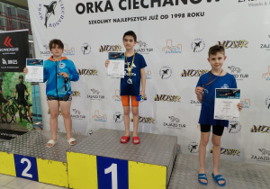 Adam Bednarek – 3 miejsce 25m stylem dowolnym. Zawodnik stoi na podium.