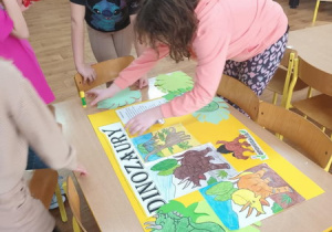 Dzieci przygotowują plakat z okazji dnia dinozaura.