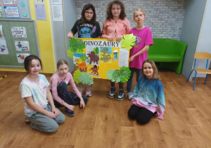 Dzieci prezentują plakat wykonany z okazji Dnia dinozaura