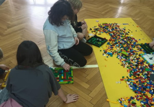 Uczestnicy półkolonii budują z kloców Lego.
