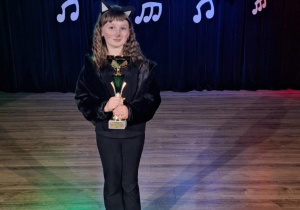 Uczennica klasy 2b - Liliana Nawrocka stoi na scenie z nagrodę za zdobycie I miejsca