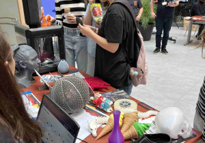 Uczennice z klasy 7c stoją przy stanowisku firmy get3D, poznają innowacyjne drukarki 3D do metalu i polimerów oraz oglądają produkty