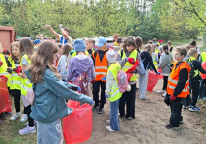 Grupa uczniów z otrzymanymi rękawicami i workami czeka na wyjście w teren.