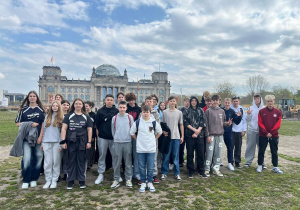 Uczestnicy wycieczki do Berlina stoją przed gmachem Reichstagu.