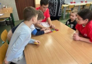 Uczeń z klasy ósmej pomaga przedszkolakom w tworzeniu robota Lego Spike.
