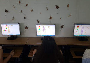 Informatyka. Programowanie sygnalizacji świetlnej, bezpieczna droga do szkoły. Prace uczniów klas 5b i 7a widoczne na ekranach komputerów.