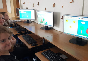 Informatyka. Programowanie sygnalizacji świetlnej, bezpieczna droga do szkoły. Prace uczniów klas 5b i 7a widoczne na ekranach komputerów.