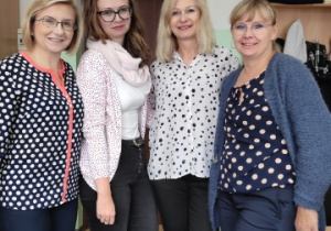 Cztery nauczycielki stojące w pokoju nauczycielskim obok siebie w ubraniach z motywem kropki.