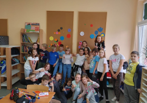 Technika. Roześmiana grupa uczniów z klasy 4c podczas zabaw w Dniu Kropki. W tle, zawieszone na tablicy kolorowe kropki wycięte przez uczniów w trakcie lekcji.
