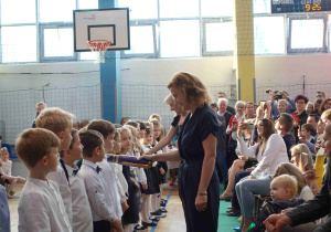 Pani dyrektor symbolicznie, wielkim piórem pasuje uczniów
