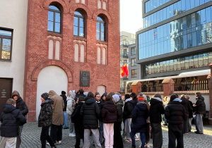 Uczestnicy wycieczki stoją przed wejściem do Muzeum Powstania Warszawskiego.