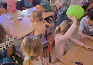 Dzieci wykonują eksperyment z wykorzystaniem balonu. Badają elektrostatyczność.