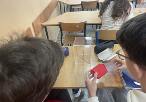 Uczniowie pracują z modelami brył aby lepiej zrozumieć pojęcia geometryczne