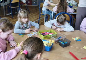 Uczniowie wykonują prace plastyczne – kolorowe ptaszki z rolek po papierze toaletowym.