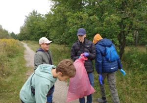 Grupa uczniów z klasy 8d zbiera śmieci na terenie Uroczyska Lublinek