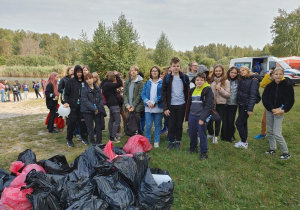 Klasa 8f znajduje się na miejscu zbiórki. Na pierwszym planie widoczne worki z zebranymi przez uczniów śmieciami