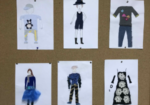 Tablica na szkolnym korytarzu z umieszczonymi pracami wykonanymi podczas techniki w klasie piątej. Stroje wykonane z różnorodnych materiałów .