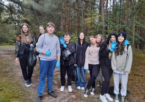 Grupa uczniów z klasy 7c zbiera śmieci na terenie Uroczyska Lublinek