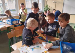 Uczniowie klas szóstych pomagają uczniom z klasy drugiej w złożeniu modeli z zestawów Lego Education Bricq