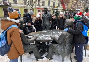 Uczniowie stoją przy Pomniku Trzech Fabrykantów