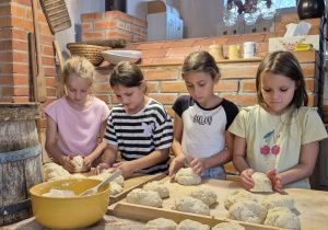 Uczniowie wygniatają ciasto i formują chlebki.