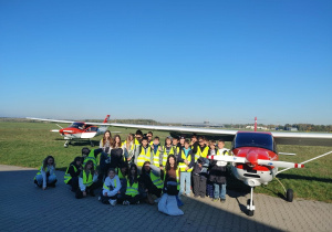 Uczniowie stoją przy samolocie treningowym Szkoły Bartolini Air.