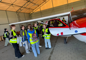 Uczniowie stoją przy samolocie treningowym Szkoły Bartolini Air.