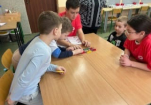Uczeń z klasy ósmej pomaga przedszkolakom w tworzeniu robota Lego Spike.