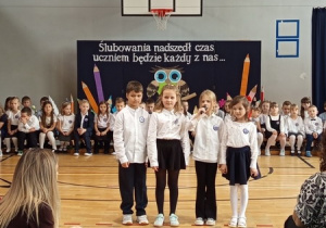 Uczniowie klas pierwszych recytujący wiersze w czasie części artystycznej.