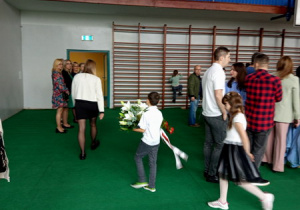 Reprezentanci klas idą złożyć kwiaty pod tablicą pamiątkową patrona naszej szkoły.