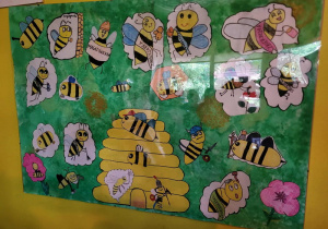 Plakat wykonany przez dzieci przedstawiający kolorowe pszczoły i ul.