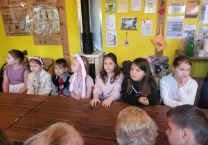 Uczniowie czekają na zajęcia , siedząc za dużym drewnianym stołem.