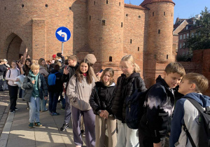 Uczestnicy wycieczki stoją przy Barbakanie.