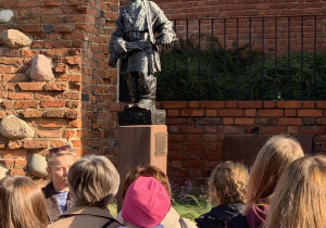 Uczniowie stoją przy Pomniku Małego Powstańca.
