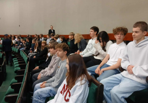 Uczniowie siedzą na Sali Posiedzeń Sejmu.