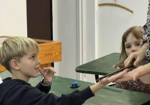 Uczeń siedzi w ławce słuchając o tym jaki kary wymierzane były dawniej w szkole. Symulowane uderzenia linijką w rękę.